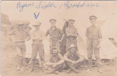 Une photographie en noir et blanc de soldats posant devant une tente.