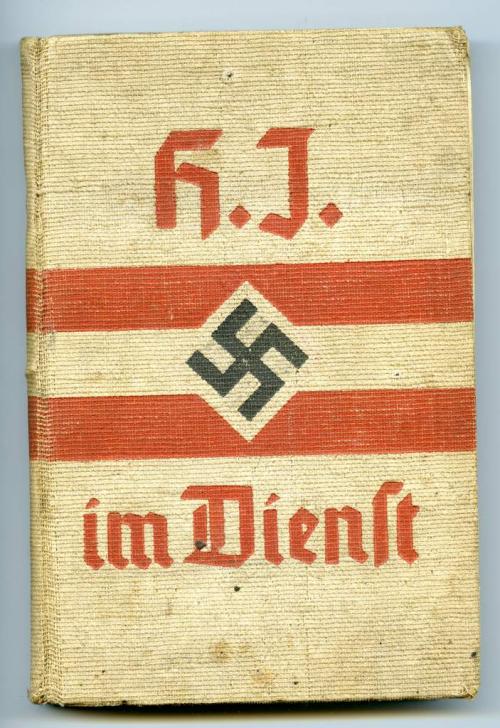 Un manuel relié beige avec de l’écriture rouge, deux rayures rouges et  une croix gammée noire au centre.