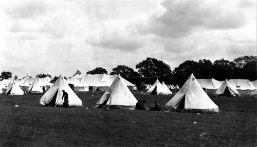 Une photographie en noir et blanc de deux groupes de soldats à côté de tentes militaires blanches au Camp Niagara.