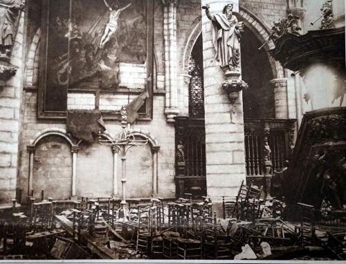 A photograph of the interior of a bombed-out church with a partially  destroyed painting of Christ.