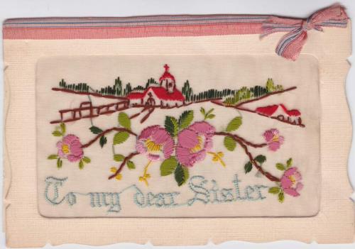 Une carte postale en tissu d’une église et d’une maison brodées adressée « À ma chère sœur ».