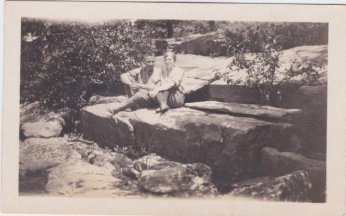 A black-and-white photograph of Byron and Mildred sitting on large rocks.