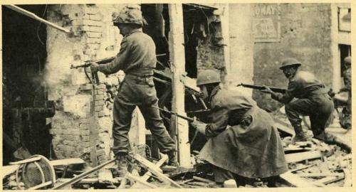 A black-and-white photograph of soldiers with guns searching bombed-out buildings.