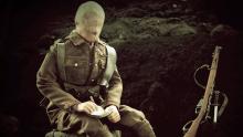 Une capture d’écran d’un mannequin-soldat assis dans une tranchée  train d’écrire une lettre.