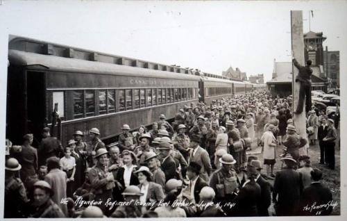 A black-and-white photograph of many soldiers boarding a train