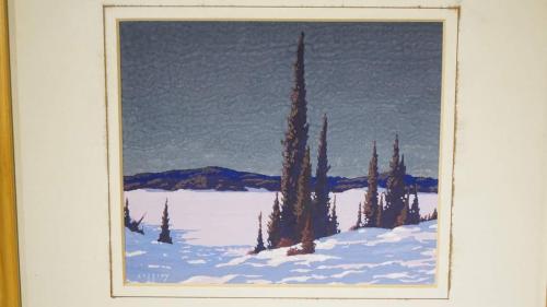 An image of a small, framed painting of a snowy landscape with a stand of conifers in the foreground.