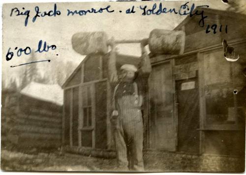Une photographie en noir et blanc de Jack Munroe soulevant  haltère de 600 livres au-dessus de sa tête.