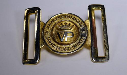 A gold-plated belt buckle inscribed with a crown and “Princess Patricia’s Canadian Light Infantry”.