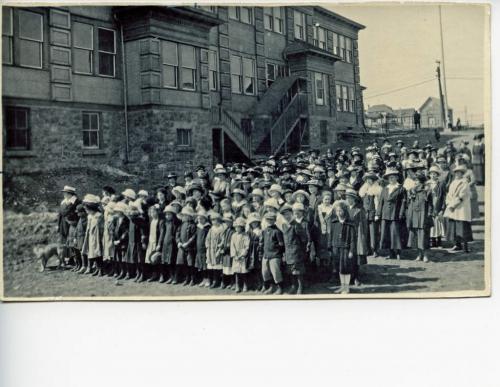 Une photographie en noir et blanc d’un grand groupe d’enfants et de femmes.