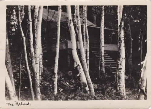A black-and-white photograph of a cabin in the woods.