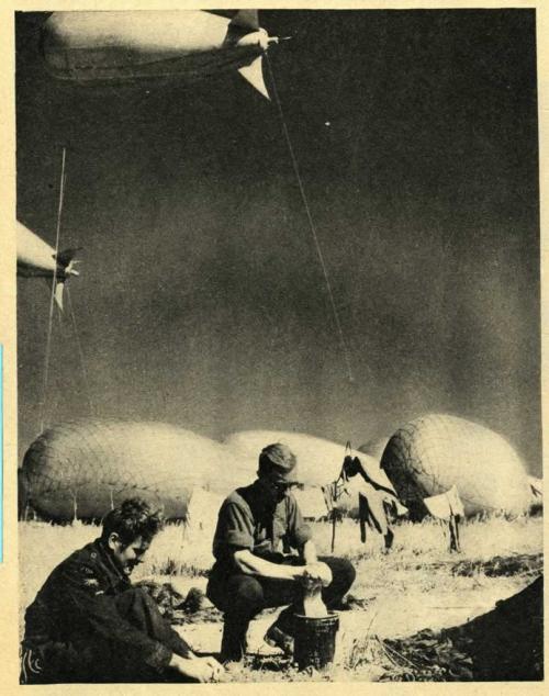 A black-and-white photograph of two soldiers washing with large balloons floating in background.