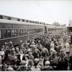 A black-and-white photograph of many soldiers boarding a train