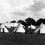 Une photographie en noir et blanc de deux groupes de soldats à côté de tentes militaires blanches au Camp Niagara.
