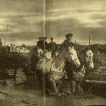 A black-and-white photograph of four horses pulling a munitions wagon along a muddy road.
