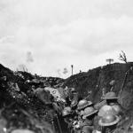 A black-and-white image of soldiers in a trench with shrapnel bursting in background.